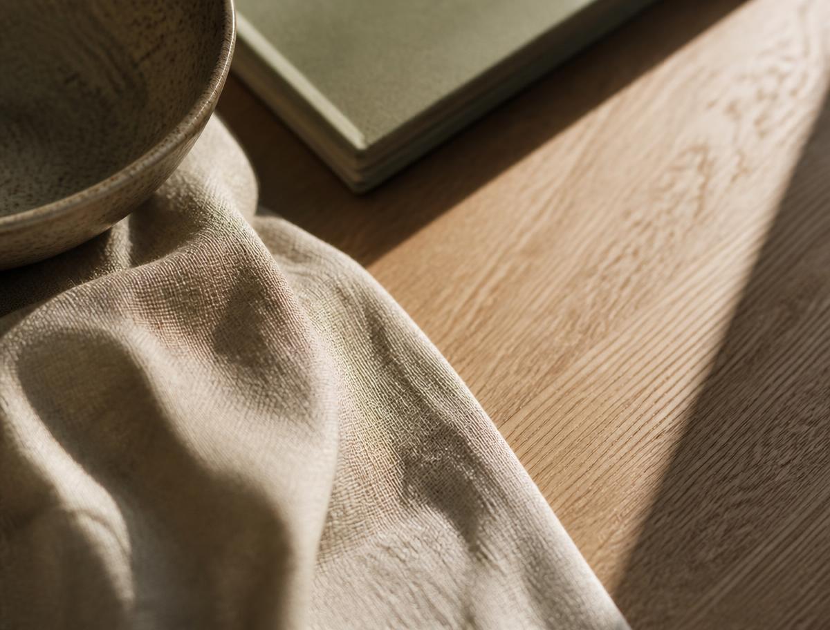 Warm natural light across a linen and oak desk surface